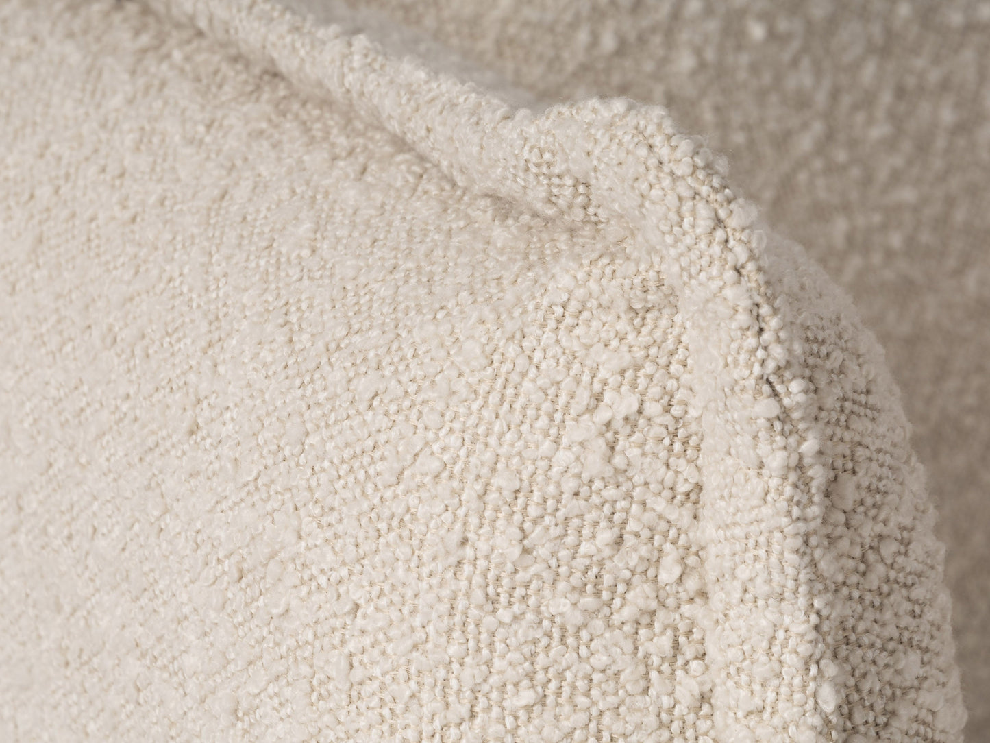 Cream Boucle Sofa with curved back, plush texture, and wooden legs. Ideal for modern living rooms. Comfortable seating with soft, tactile fabric.