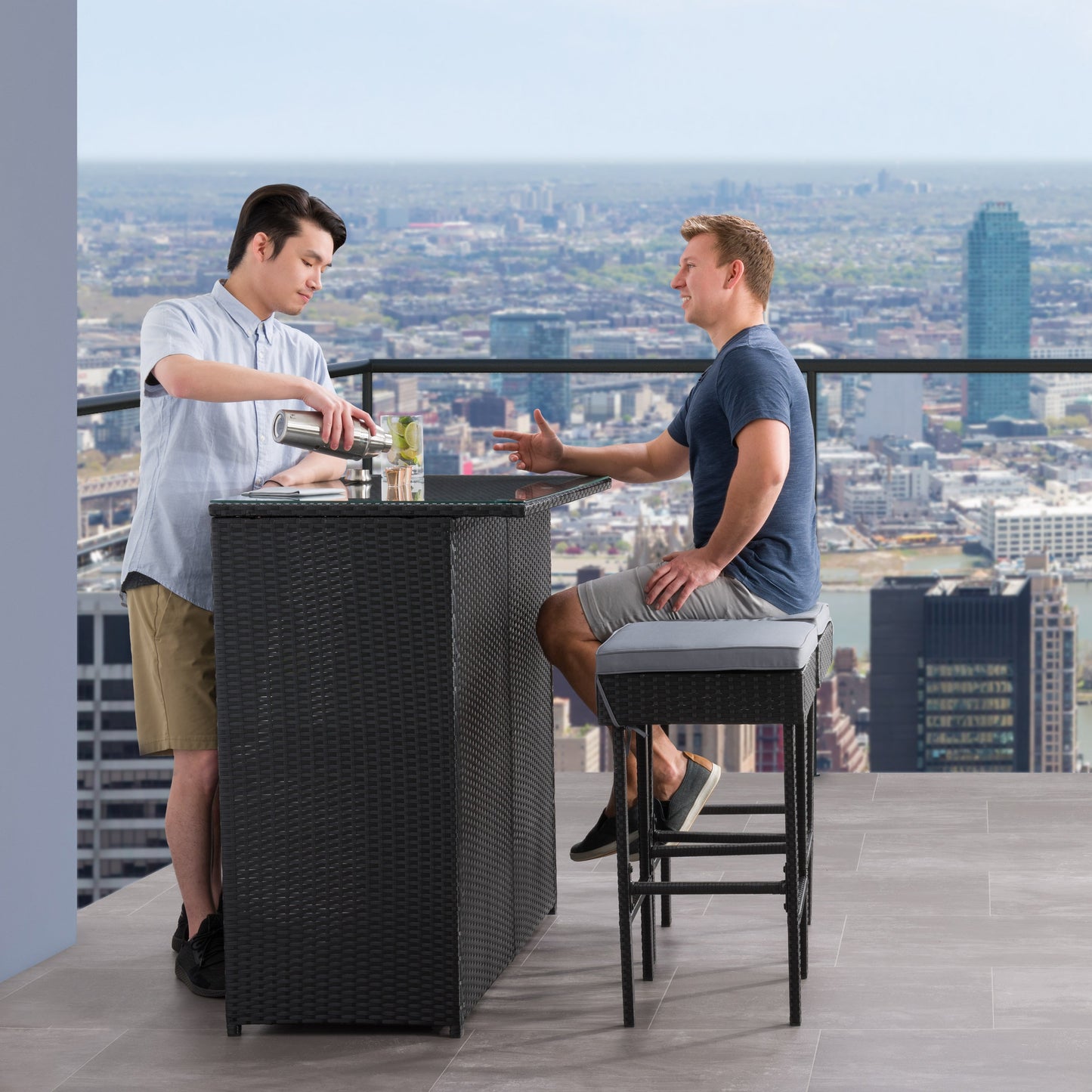 Three-piece patio bar set featuring a high table and two bar stools with beige cushions, crafted from durable, weather-resistant dark brown wicker, perfect for outdoor entertaining and relaxation.