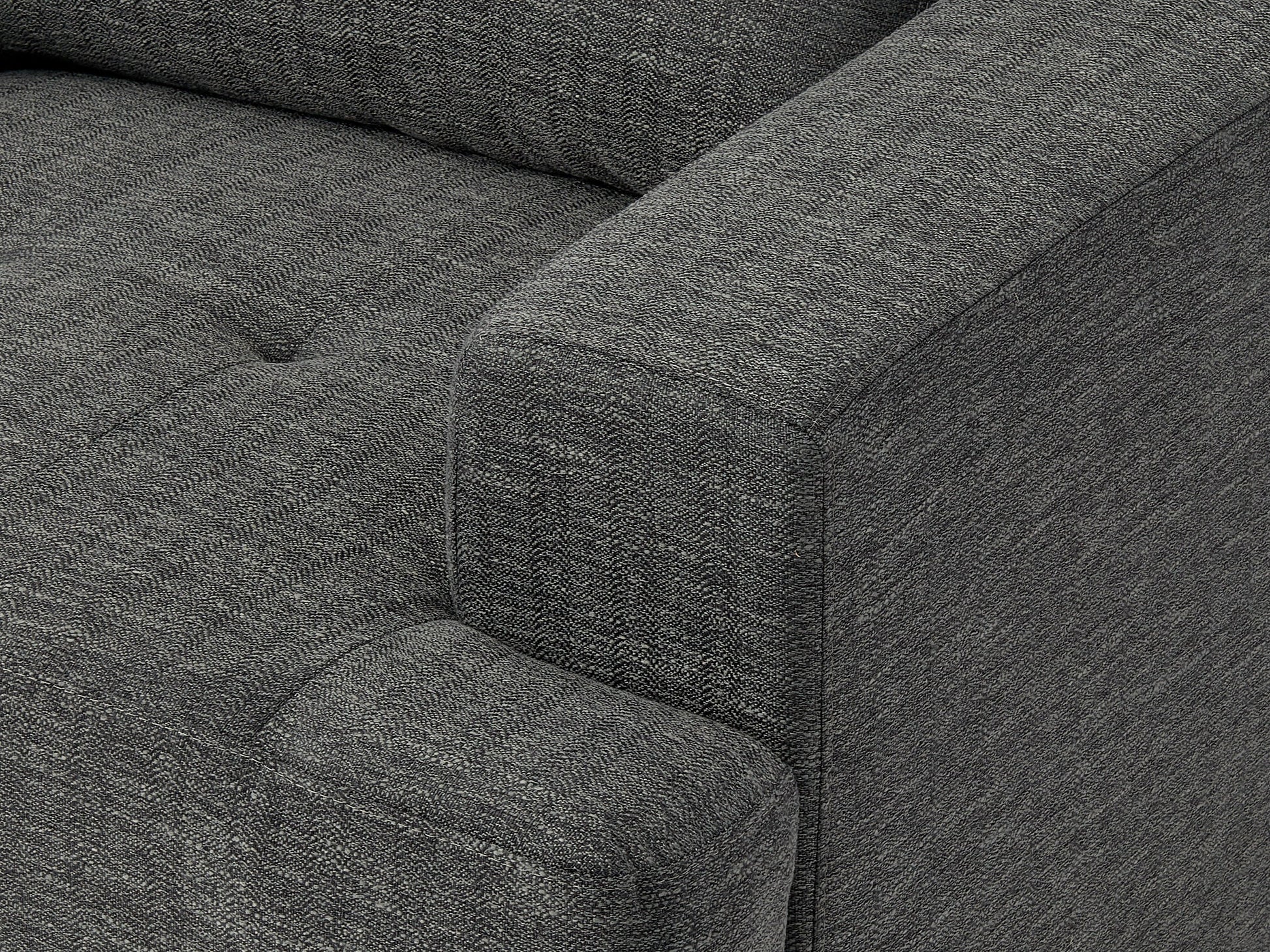 Dark grey mid-century armchair with wooden legs, upholstered in soft fabric, featuring a tufted backrest and padded seat, ideal for modern living rooms or offices.