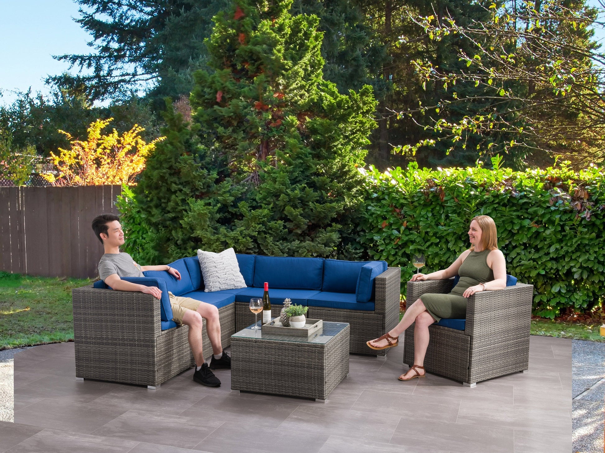 Outdoor sectional set, 7-piece, featuring weather-resistant wicker in a neutral gray tone with plush, water-resistant cushions in beige. Includes modular seating and a glass-top coffee table, perfect for patio relaxation.