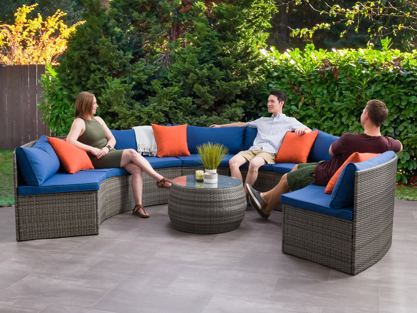 Circular outdoor patio sectional, 5-piece set with beige cushions and brown wicker frame, featuring a round coffee table with glass top, perfect for garden or backyard lounging.